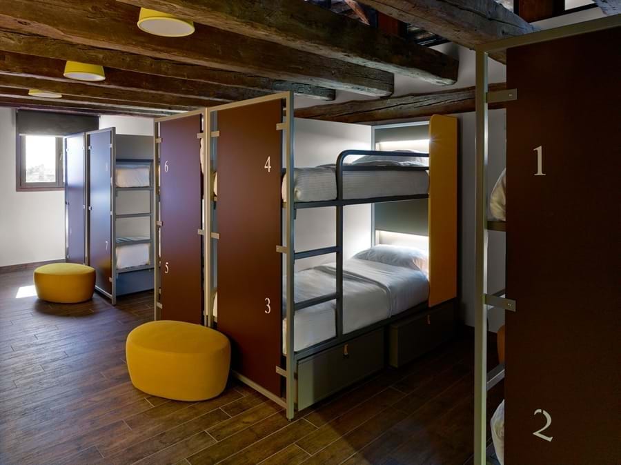 Lit dans un grand dortoir – Salle de bains commune